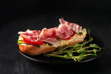 Domuz pastırmalı, salatalıklı ve domatesli taze ev yapımı sandviç.