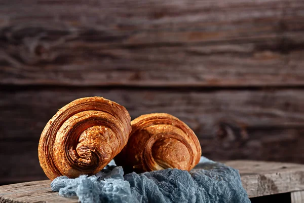 Frisch gebackene duftende Croissants auf einem Holzgrund — Stockfoto