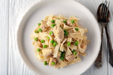 Beyaz ahşap arka planda yeşil bezelye, tavuk ve krema soslu ev yapımı makarna.
