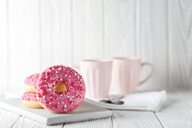 Pembe jöleli çörekler ve beyaz ahşap arka planda renkli karamel tozu..