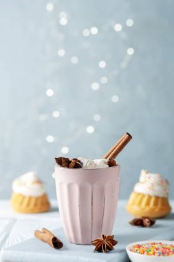 A cup of cocoa with marmallows and vanilla muffins with cream cheese cream. Copy space.