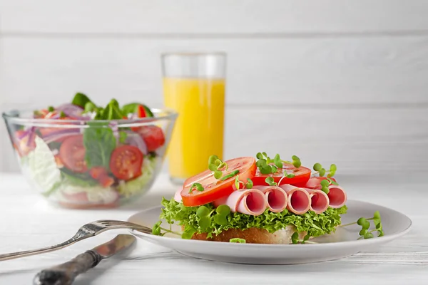Sandwich with sausage and tomatoes, with salad and orange juice. European breakfast. — Stock Photo, Image
