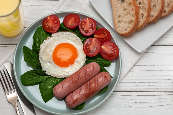 Gebratene Eier mit Würstchen, Spinat, Tomaten, Toast und Orangensaft auf weißem Holzgrund. Europäisches Frühstück. — Stockfoto