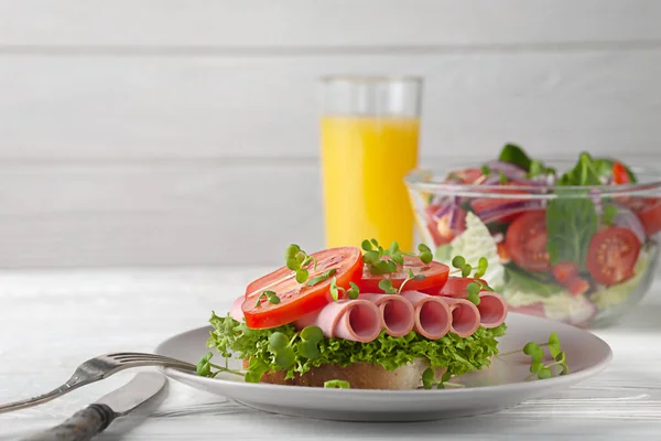 Sandwich with sausage and tomatoes, with salad and orange juice. European breakfast. — Stock Photo, Image
