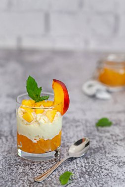 Peach fruit dessert in a glass cup with curd cream and peach jam. Homemade fruit dessert.