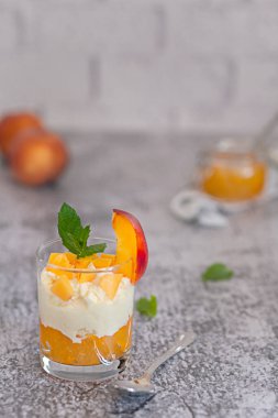 Peach fruit dessert in a glass cup with curd cream and peach jam. Homemade fruit dessert.