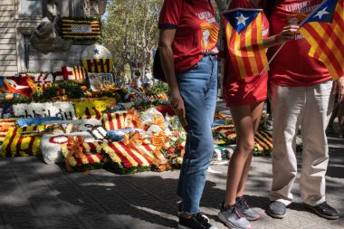 Diada Günü, Katalan milliyetçiliğinin bir simgesi olarak kabul edilen Rafael Casanova 'nın anısına anıtı çevreleyen çiçeklerin önünde poz veren tanınmamış insanlar..