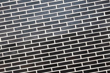 Beyaz harç çizgisi olan siyah tuğla bir duvar dokusu, eğimli bir düzlem. Kopyalama alanı olan soyut arkaplan