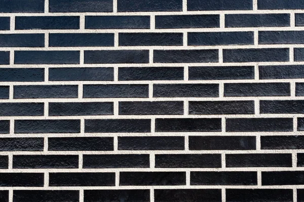 A rectangular black brick wall texture with white grout, horizontal orientation. Abstract background with copy space.