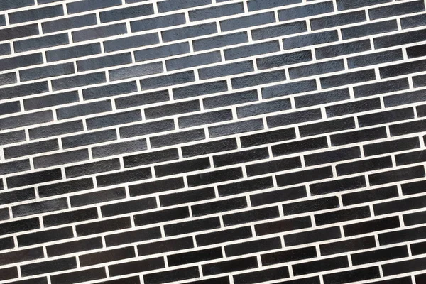 Beyaz harç çizgisi olan siyah tuğla bir duvar dokusu, eğimli bir düzlem. Kopyalama alanı olan soyut arkaplan