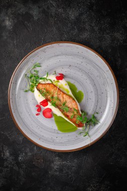 Baharatlı ızgara somon bifteği ve koyu taş bir masada bezelye filizi. 