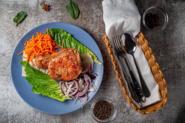 Serving a dish from the restaurant menu. Grilled beef and pork meat with grated carrots and herbs on a plate against a gray stone table, delicious kebab