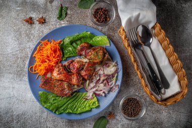 Serving a dish from the restaurant menu. Grilled beef and pork meat with grated carrots and herbs on a plate against a gray stone table, delicious kebab