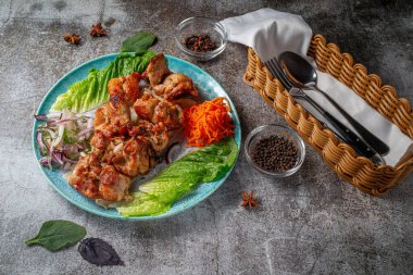 Serving a dish from the restaurant menu. Grilled beef and pork meat with grated carrots and herbs on a plate against a gray stone table, delicious kebab