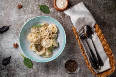 Meat dumplings with spices on a plate with greens against the background of a gray stone table 
