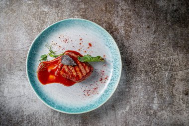 Grilled delicious beautiful meat steak in a blue plate with cutlery and a napkin on a stone table in a restaurant