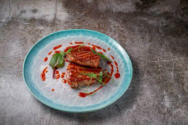 Grilled delicious beautiful meat steak in a blue plate with cutlery and a napkin on a stone table in a restaurant