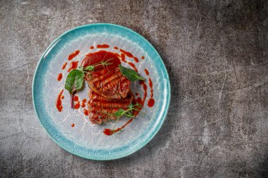 Grilled delicious beautiful meat steak in a blue plate with cutlery and a napkin on a stone table in a restaurant