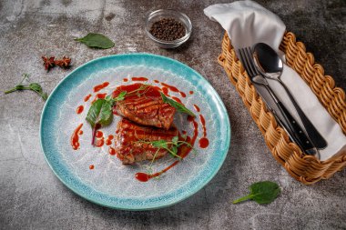 Grilled delicious beautiful meat steak in a blue plate with cutlery and a napkin on a stone table in a restaurant