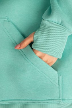 Sweatshirt 'ün cebindeki bir kızın yakın plan fotoğrafı. Spor kazak giyen bir kadının fotoğrafının bir parçası. Modaya uygun spor kıyafetleri reklamı. Mavi renk