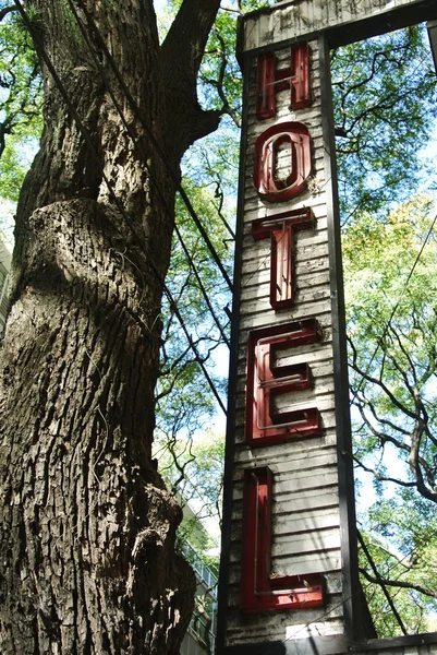 Worn out hotel sign and tree — Stock Photo, Image