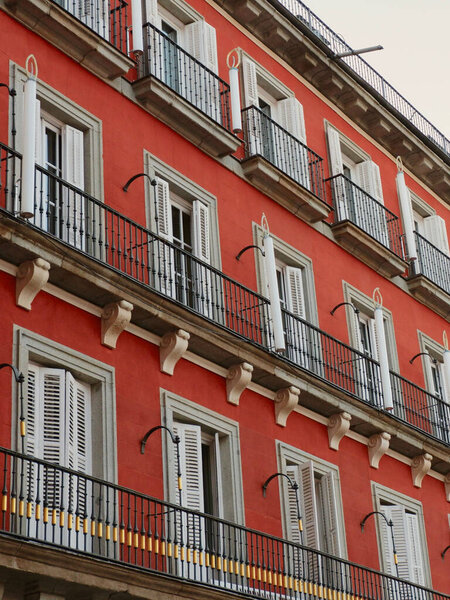 Festive red facade in classical style downtown in Madrid, Spain. Exterior of classic renaissance building. Vertical photo.