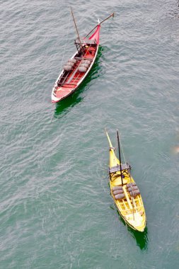 Aerial view on wooden boats of yellow and red colours on Douro river in Porto, Portugal.