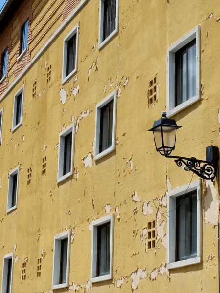 Weathered facade with peeling yellow paint in the old center of Segovia, Spain.