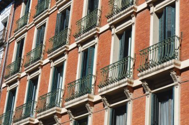 Madrid, İspanya 'daki binanın ön cephesinde panjurları ve küçük balkonları olan pencereler..
