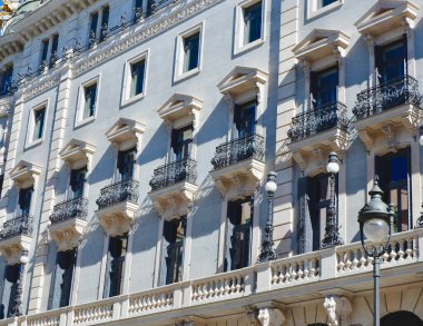 Elegant noble facade of the building lit by sun in the central district of Madrid, Spain.
