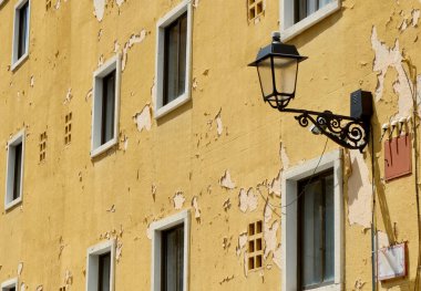 Damaged facade with simple windows and yellow peeling paint in Segovia, Spain.