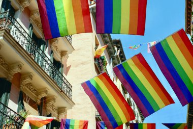 Madrid 'in Chueca semtinin sokaklarında balkonların arasında gökkuşağı bayrağı asılı. Eşcinsel gururu ayındaki tören süsleri.