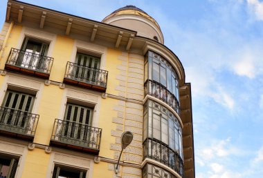 Tarihi klasik binanın yuvarlak köşesinde zarif metalik balkonları ve eski ahşap kepenkleri olan pencereleri var. Madrid, İspanya 'nın zarif İspanyol mimarisi.