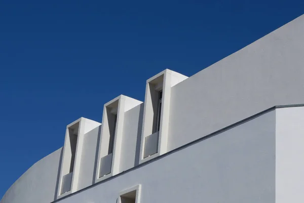 Minimal lines of modern white building against saturated blue sky. Lined minimalistic architecture.