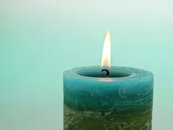 Close up of burning candle against blue background — Stock Photo, Image