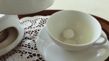 Kaya şekeri ve krema ekleyerek bir fincana siyah çay dökmek
