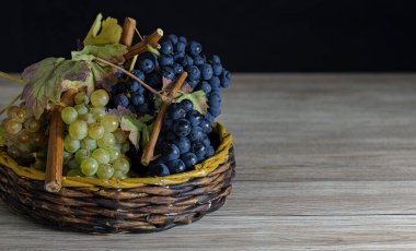 Tahta masadaki sepetin içinde doğal beyaz ve mor üzümlü bir resim.