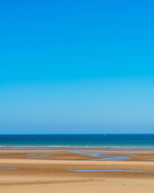 Beautiful image with sand of beach, calm ocean and clear sky in background.