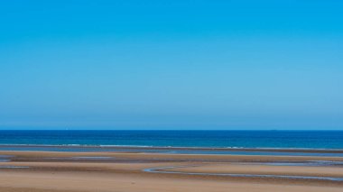 Natural view of ocean with sand of beach and clear sky on summer days