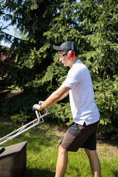 Gardener mowing the grass with a gasoline lawn mower