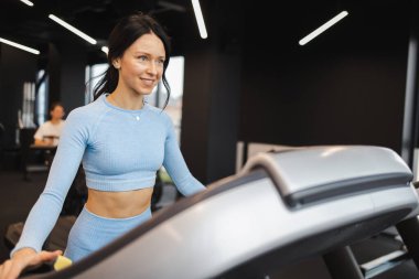 Koşu bandında egzersiz yapan güzel bir esmer.