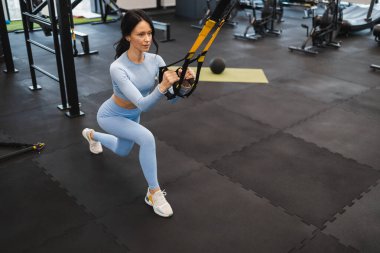 Spor salonunda TRX egzersizleri yapan bir kadın.