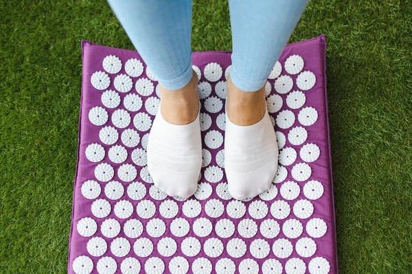 Women\'s feet standing on acupressure mat. Acupuncture massage