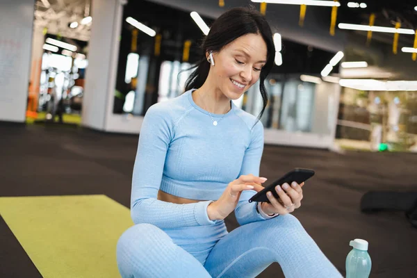 Fröhliche Fitness Frau Mit Drahtlosen Kopfhörern Sitzt Fitnessstudio Auf Dem — Stockfoto