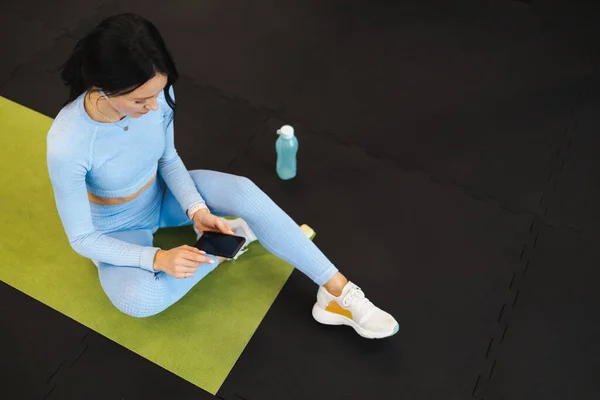 Attractive Fitness Woman Headphones Using Smartphone While Sitting Yoga Mat — 图库照片