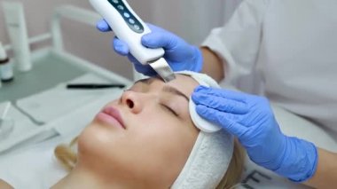Ultrason cihazıyla yüz temizleme. Kadın ultrasonda yüz soyma ve temizleme ameliyatı oluyor. Kozmetoloji ve yüz bakımı. Yüz tedavisi