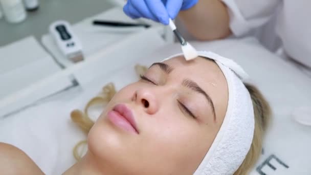 美容师用刷子刷面部剥皮面膜 女性皮肤手术 美容师在美容院的病人脸上涂上油 — 图库视频影像
