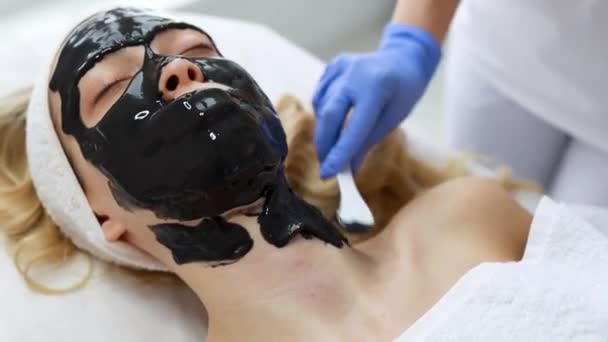 Beautist Appliceras Patientens Ansikte Svart Mask Huden Med Spatel — Stockvideo