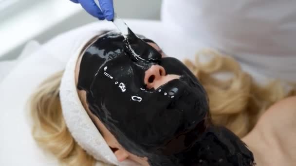 Schoonheidsspecialiste Aangebracht Patiënt Gezicht Een Zwart Masker Huid Met Een — Stockvideo