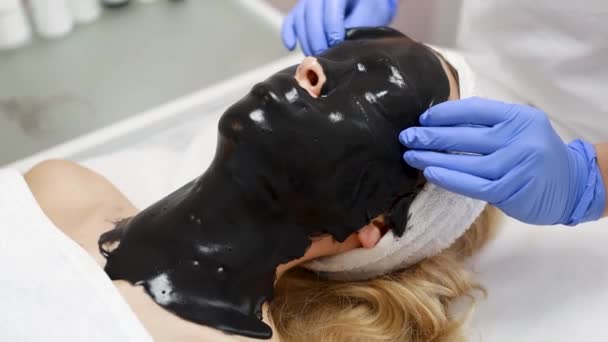 Kosmetologe Entfernt Die Schwarze Gesichtsmaske Aus Dem Gesicht Des Patienten — Stockvideo